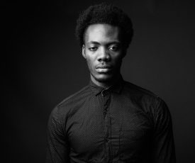 Studio shot of young handsome African businessman against gray background in black and white